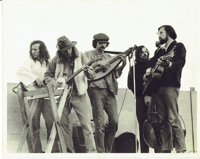 An early 1970s photo of Rick Scott playing a Rick (JR) Stone dulcimer in his first band Pender Harbour Fats and the Mother Furriers. Rick Scott is in faux leopard poncho, Rick (JR) Stone on far right, in Gibsons Landing, British Columbia, Canada.